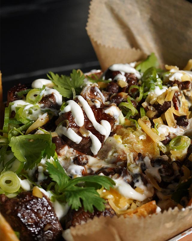 Loaded fries topped with beef, cheese, and cilantro at Red Crown sports bar, a favorite happy hour starter